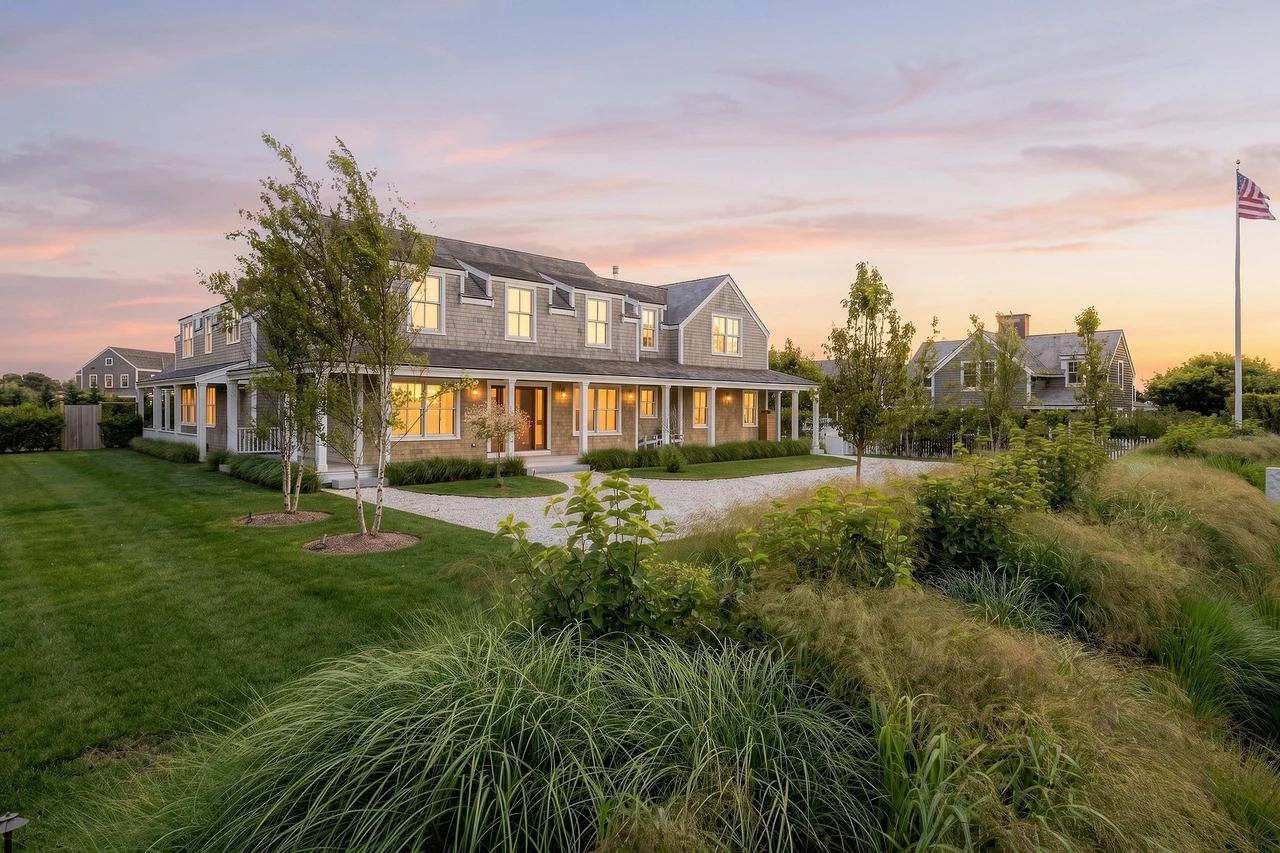 Twilight front view of Nobadeer with illuminated windows, a covered porch and landscaped grounds