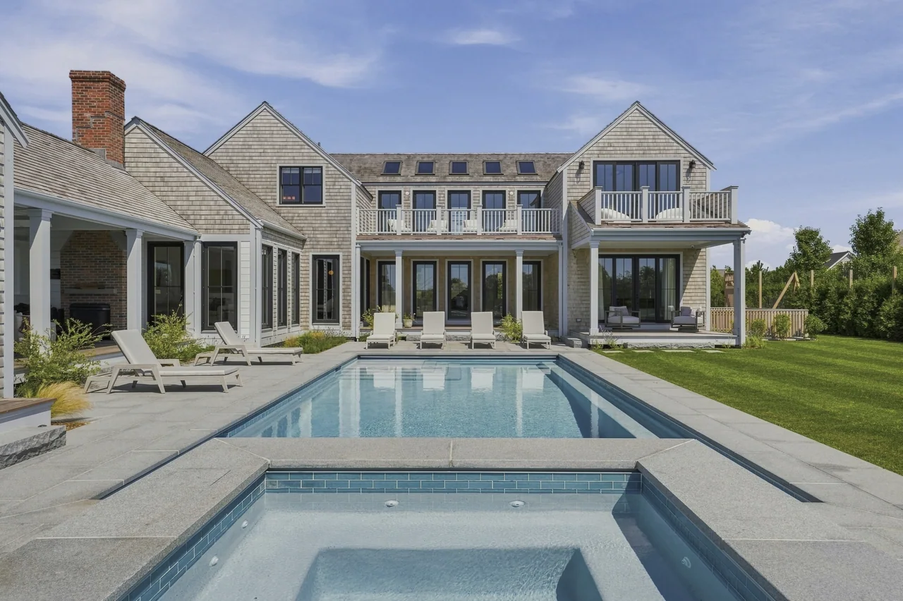 Cedar-shingle residence and covered porches beyond the pool and spa
